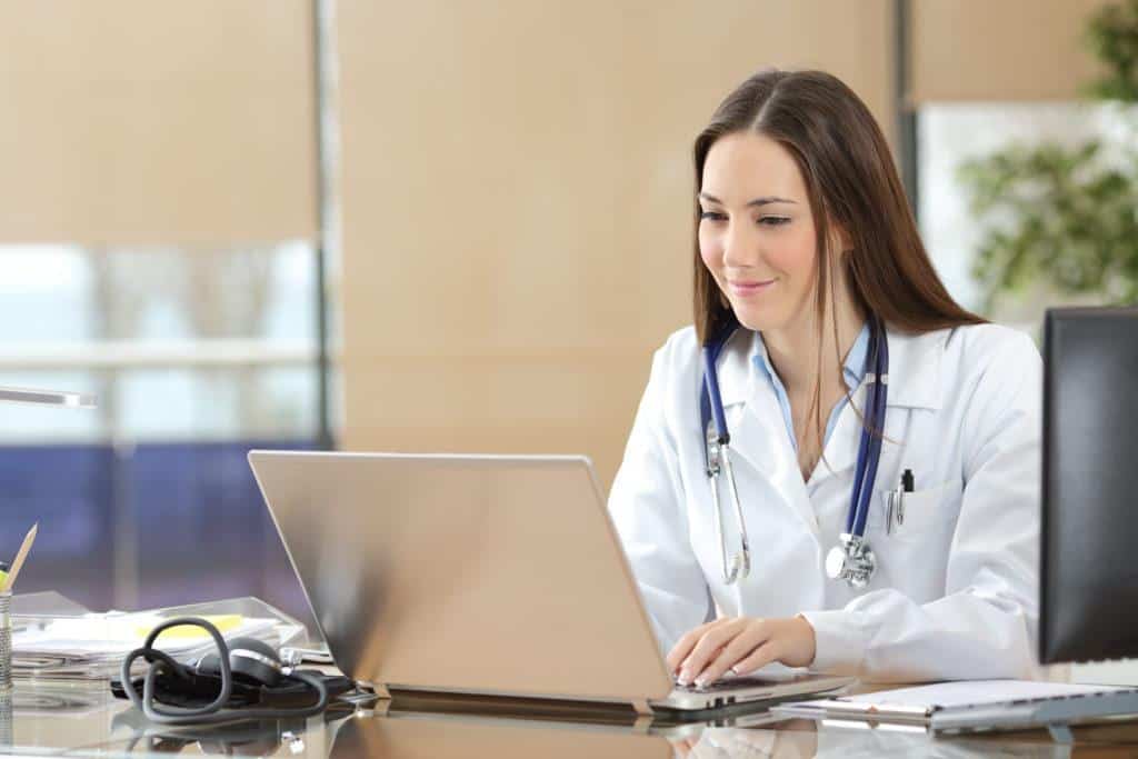 a doctor is sitting at a desk using a laptop computer