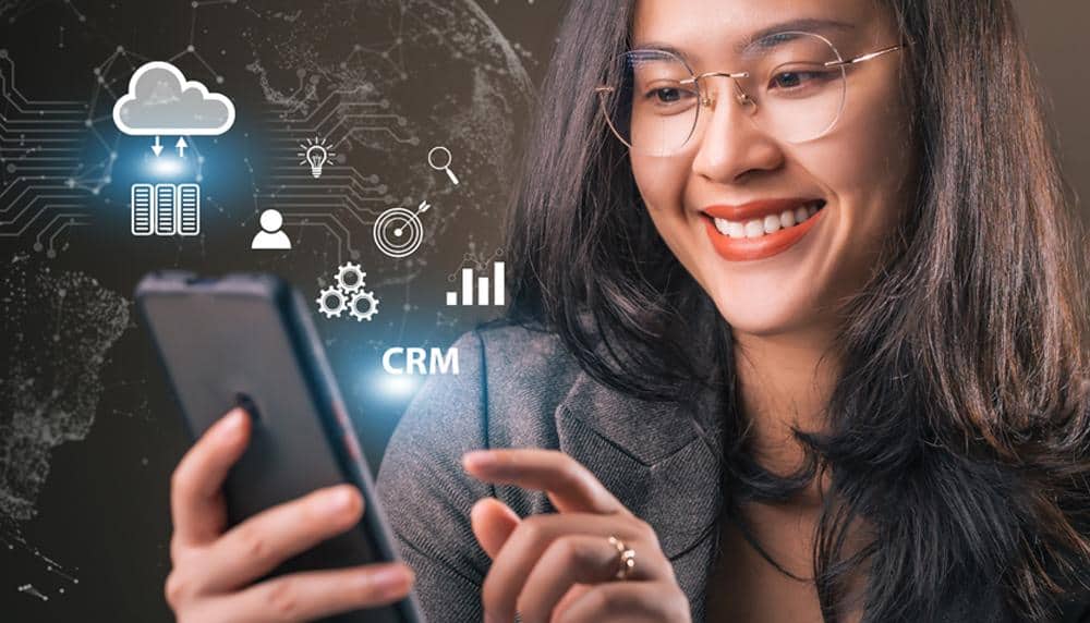 A Woman Wearing Glasses is Smiling While Looking at Her Cell Phone