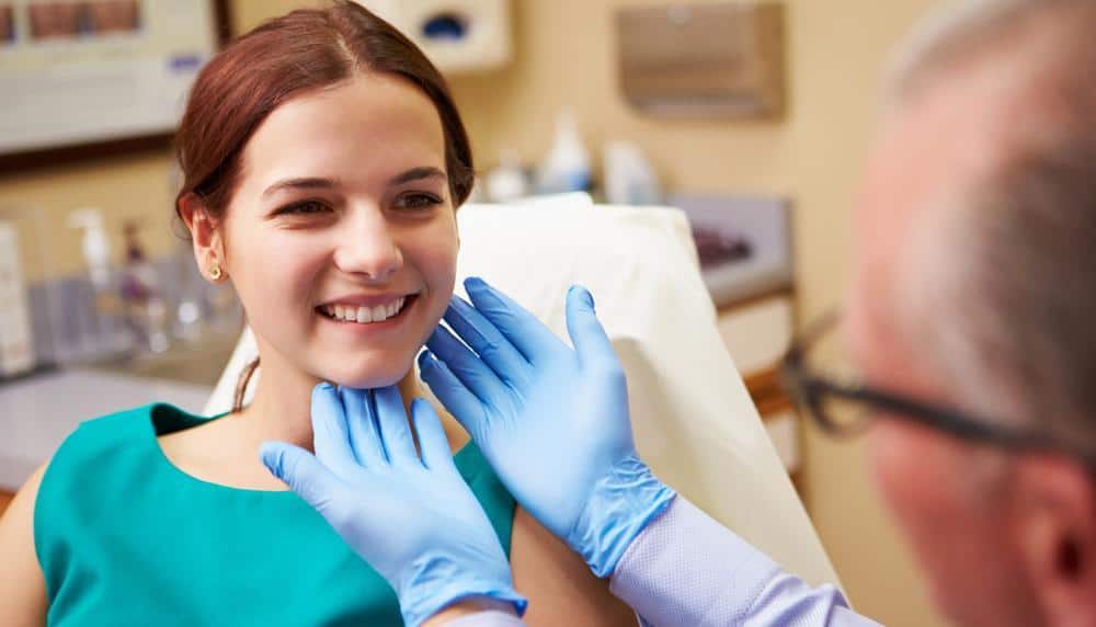 A Woman is Smiling While a Doctor Examines Her Face