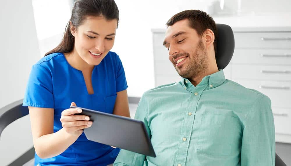 a dentist is showing a tablet to a patient