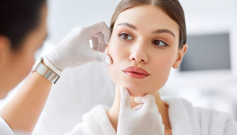 a woman is getting her face examined by a doctor