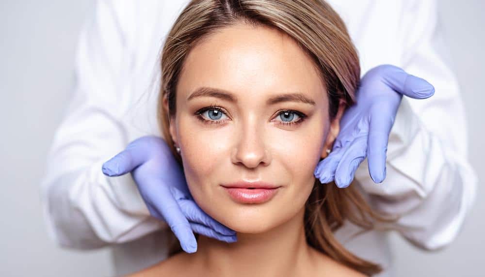 a woman is getting her face examined by a doctor wearing gloves