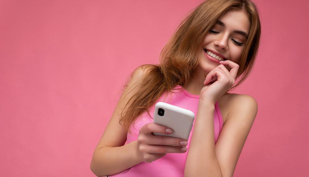 A Woman Wearing Pink Smiling at Her Phone