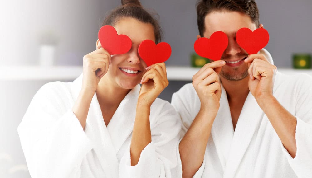 A Man And A Woman Covering Their Eyes With Red Hearts